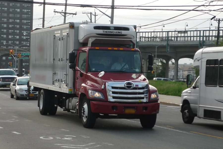 Red Hino conventional truck with a refrigerated box and Thermo King unit