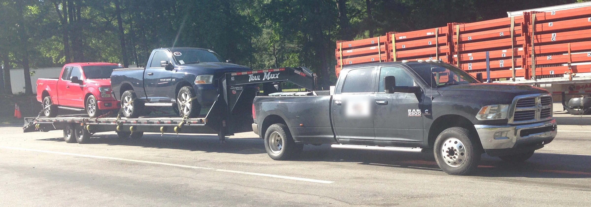 Ram 3500 dually pickup towing a gooseneck flatbed trailer loaded with two pickups