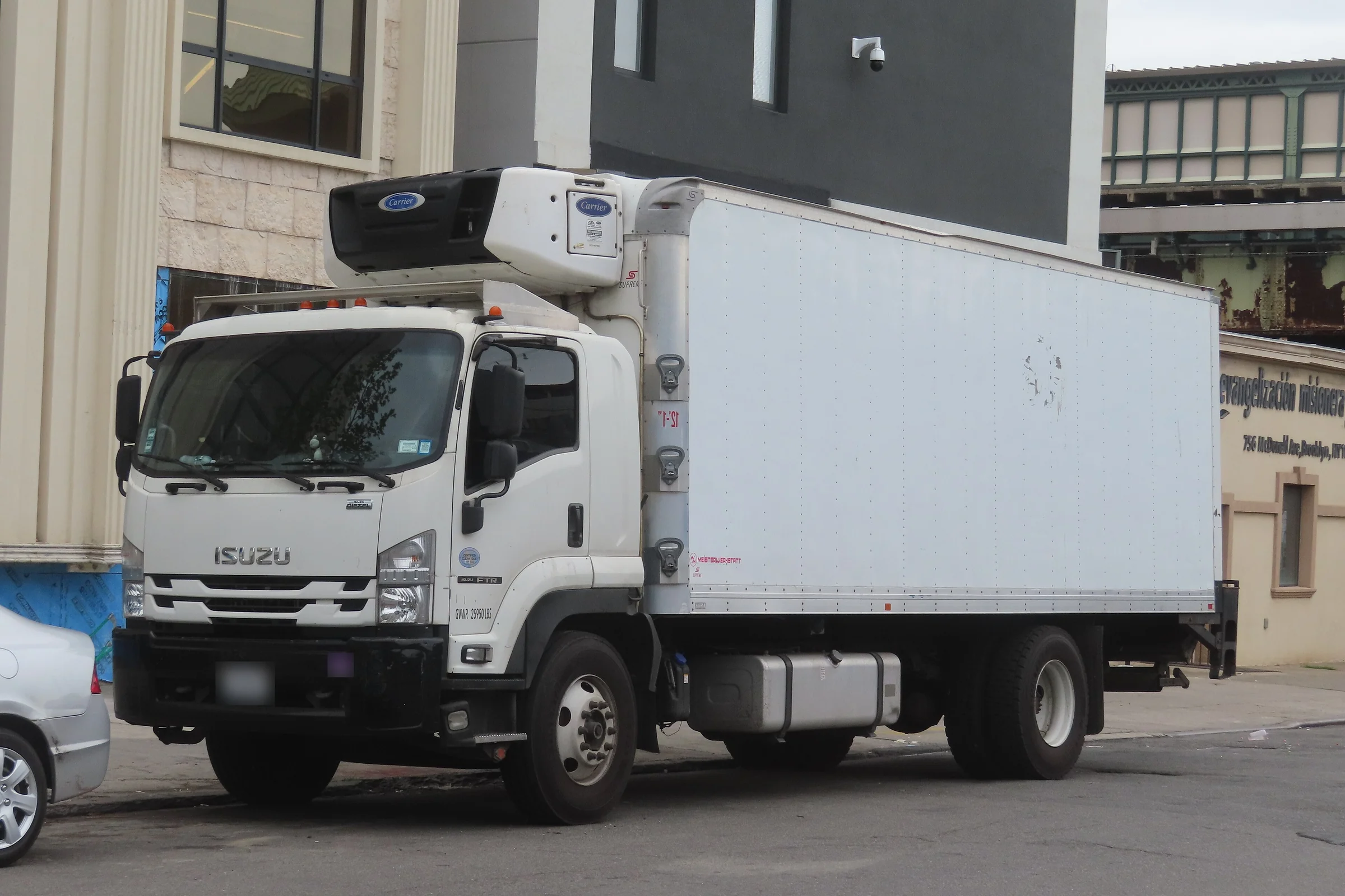 White Isuzu FTR cab-over truck with a refrigerated box