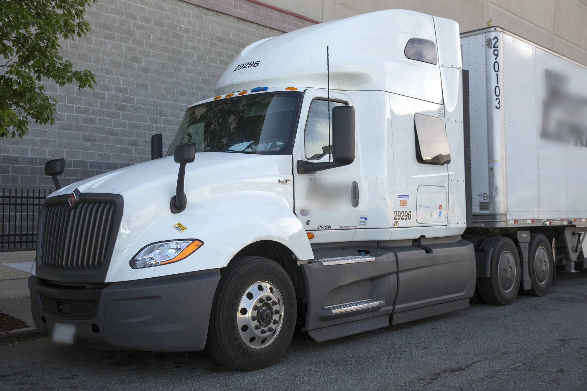 White International LT sleeper tractor coupled to a trailer, parked beside a brick building